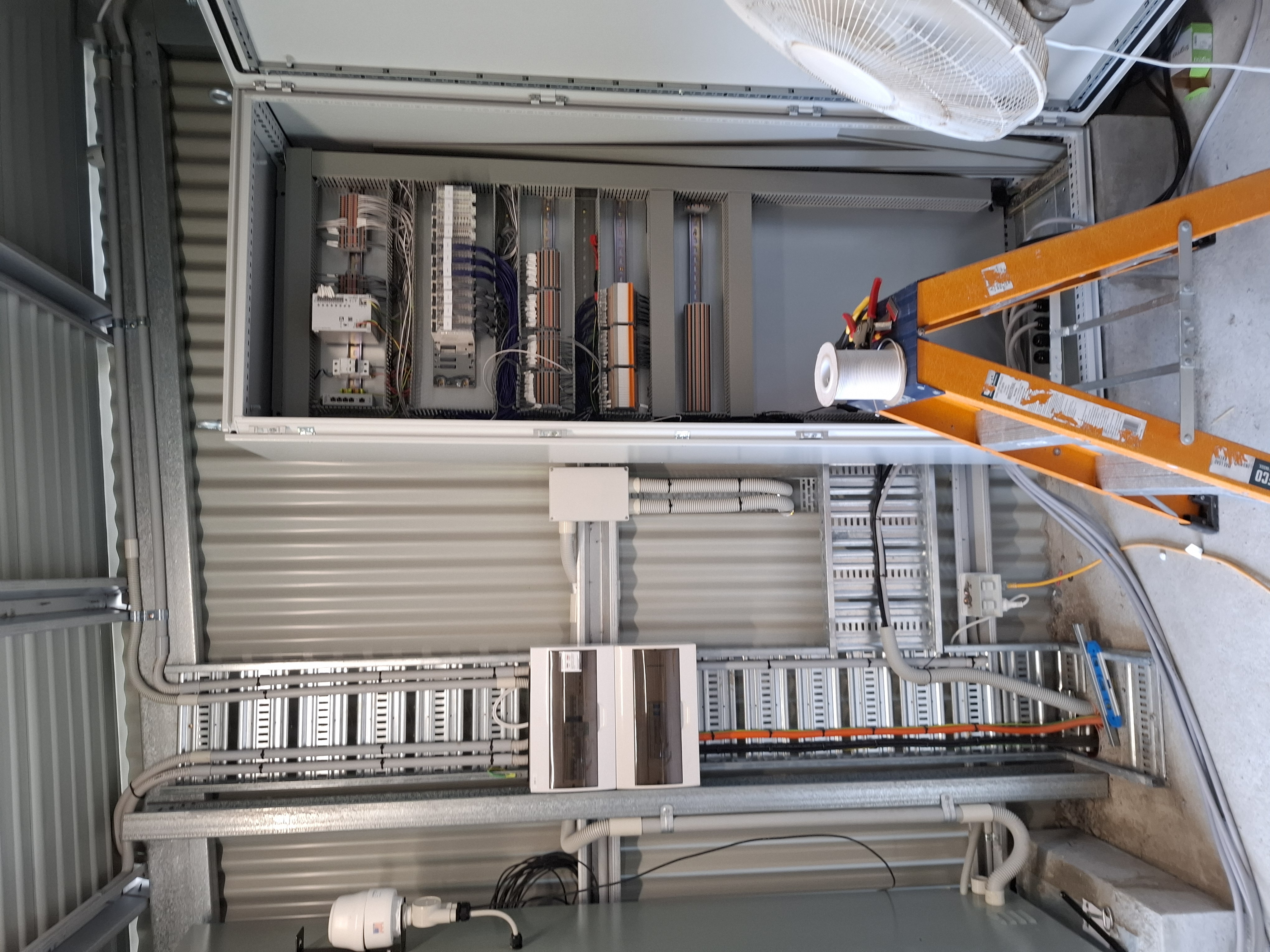 New Eco Village RWTP control cabinet — PLC rack, terminal strips and DIN-rail-mounted relays during commissioning